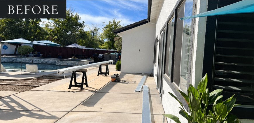 Bare concrete patio beside a pool before the louvered pergola installation
